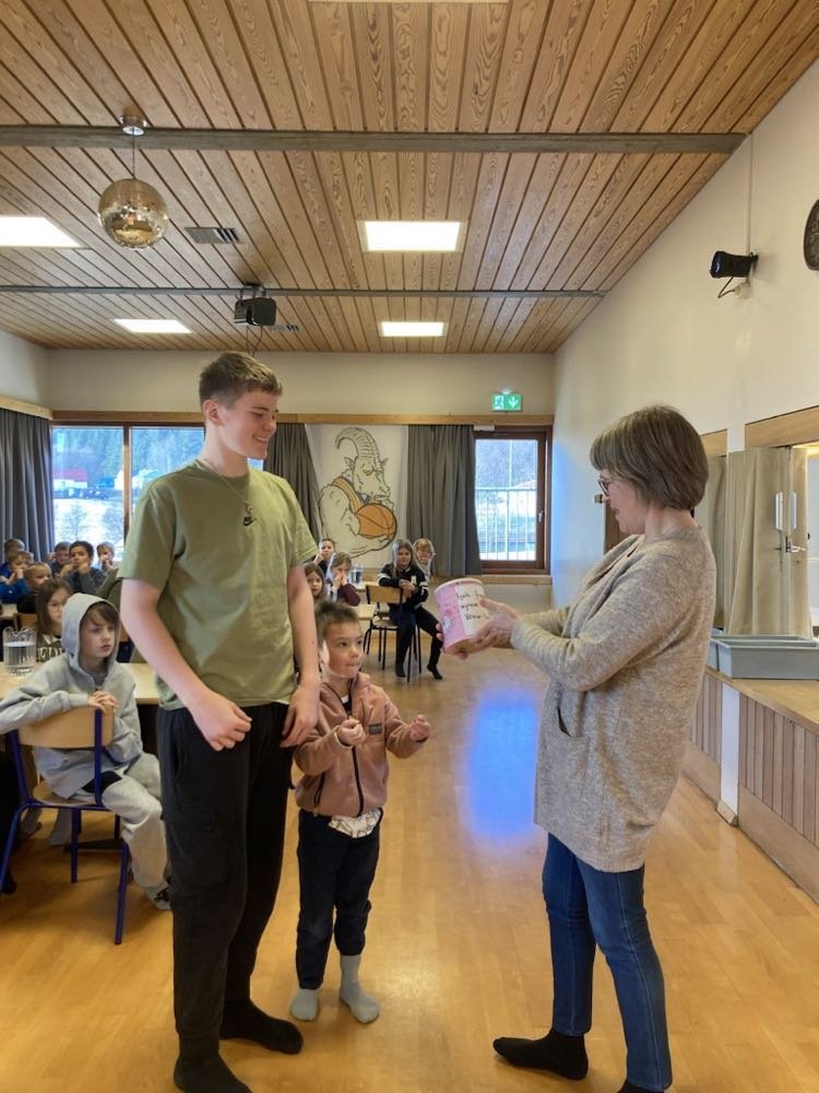 Þórunn Júlíudóttir tekur við söfnunarbauk úr hendi yngsta nemandans og þess elsta.