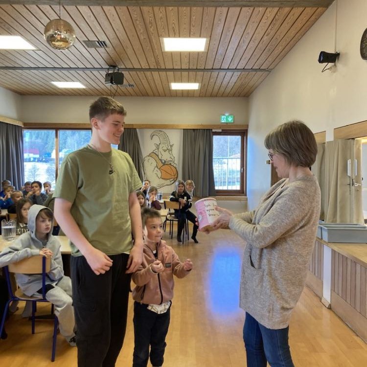 Þórunn Júlíudóttir tekur við söfnunarbauk úr hendi yngsta nemandans og þess elsta.